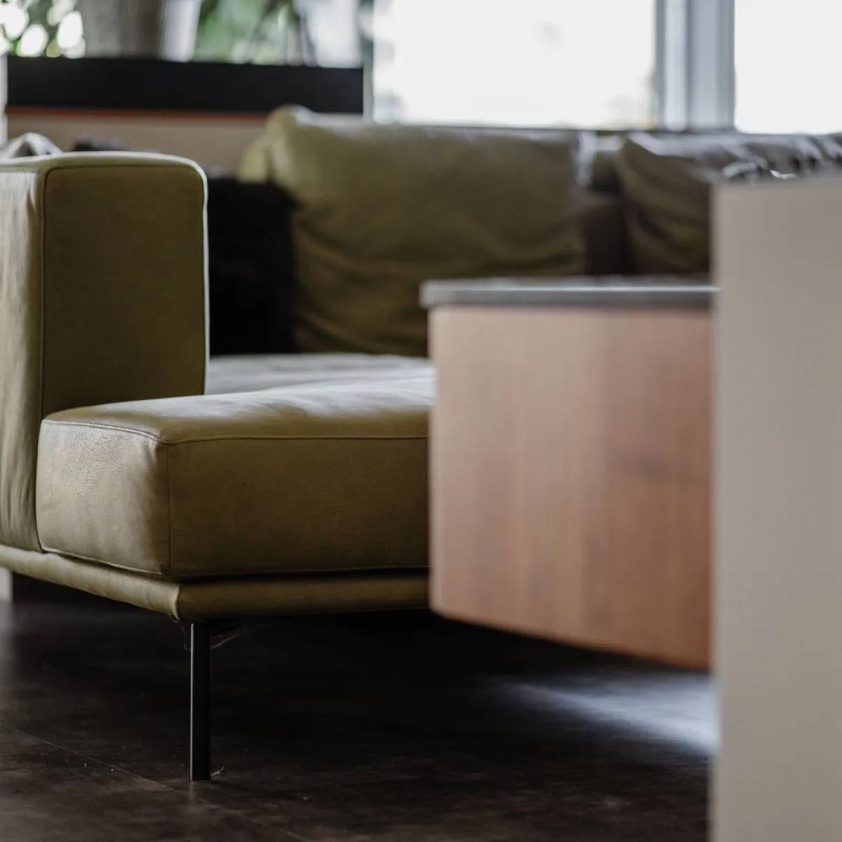 Detail einer Möbelkante neben einem olivgrünen Sofa