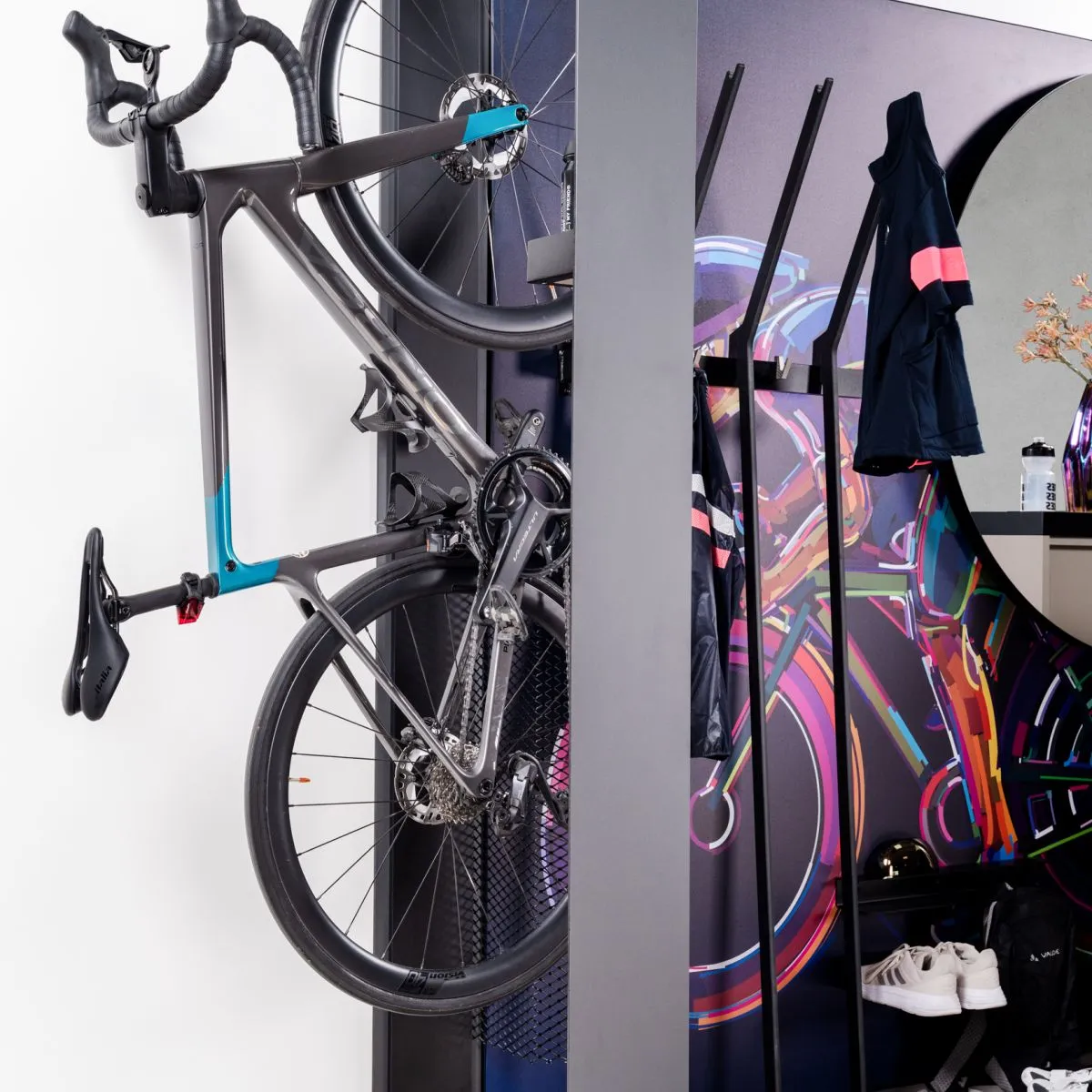 Fahrrad an einer Wandhalterung neben Kleidung